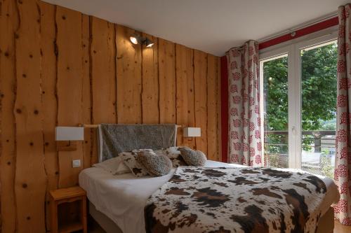 een slaapkamer met een bed in een kamer met houten wanden bij Logis Hôtel Restaurant Le Castel Fleuri in Saint-Jean-en-Royans