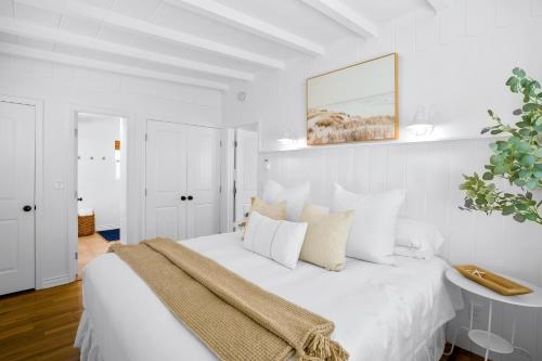 a white bedroom with a white bed with a blanket on it at Newport Beach Cottage B in Newport Beach