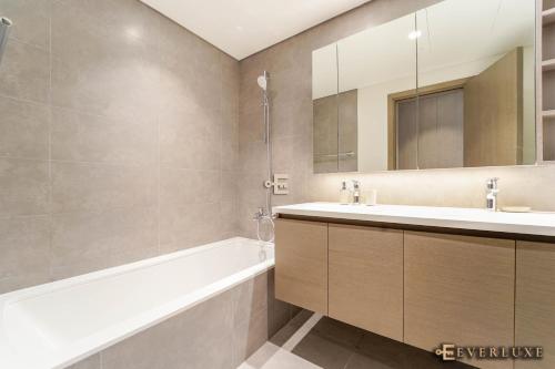 uma casa de banho com um lavatório, uma banheira e um espelho. em Smart 3 Bed In Creek Gatefully Furnished Wbills em Dubai