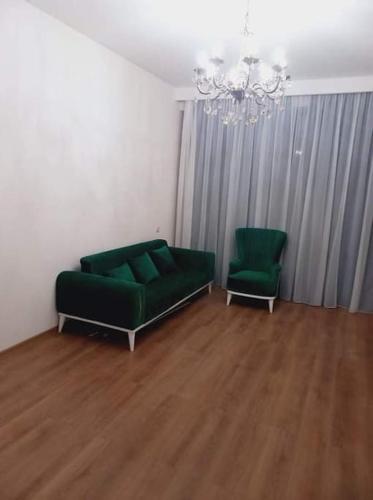 een woonkamer met een groene bank en 2 stoelen bij Apartment in Politovskaia st in Agaraki