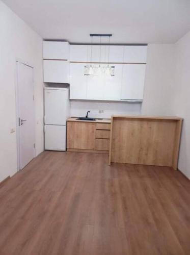 een keuken met witte kasten en een houten vloer bij Apartment in Politovskaia st in Agaraki