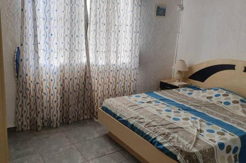 a bedroom with a bed and a window with curtains at Appartment et piscine in Flic-en-Flac