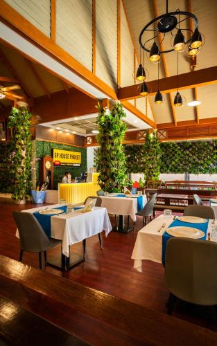 a restaurant with tables and chairs and plants at GP House Phuket Patong Beach in Patong Beach
