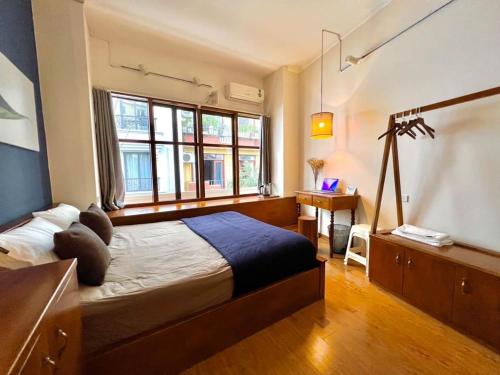 a bedroom with a bed and a desk and windows at Nice room located right next to the Old Quarter Căn phòng nhiều ánh sáng tại ngay gần phố đi bộ Hồ Gươm in Hanoi