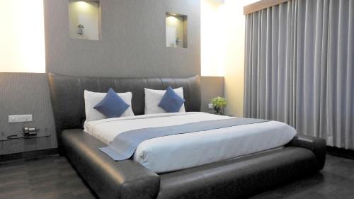 a bedroom with a large bed with blue pillows at Hotel Sai Miracle in Shirdi