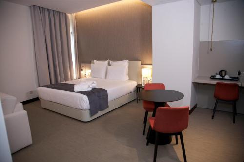 um quarto de hotel com uma cama, uma mesa e cadeiras em Hotel Continental Horizonte em Luanda