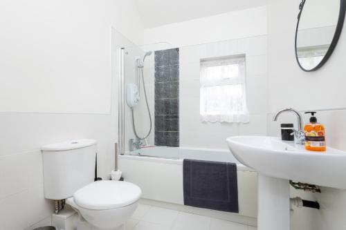 a white bathroom with a toilet and a sink at Wakefield Canal Cottage - Parking, Self Check-in, Fast WiFi, Large Garden, Canal Side Views - Contractors, Families, Long Stays in Wakefield