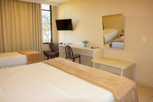 a hotel room with a bed and a desk and a mirror at Hotel Diplomat in Brasilia