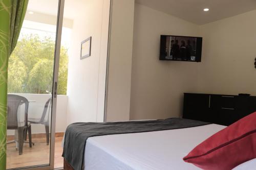 a bedroom with a bed and a table and a window at Hosteria La Medusa in Cocorná