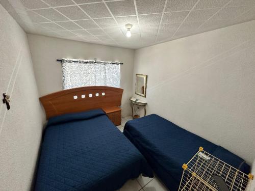 1 dormitorio con 2 camas azules y ventana en Casa de descanso alberca climatizada, en Atlixco