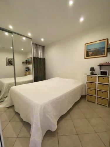 une chambre avec un lit blanc et un miroir dans l'établissement Appartement T3 plain pied terrasse wifi 4SARD32 Apartment ground floor, terrace and wifi, à Canet
