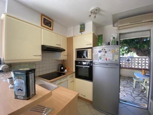 une cuisine avec un réfrigérateur et une table à l'intérieur dans l'établissement Appartement T3 plain pied terrasse wifi 4SARD32 Apartment ground floor, terrace and wifi, à Canet