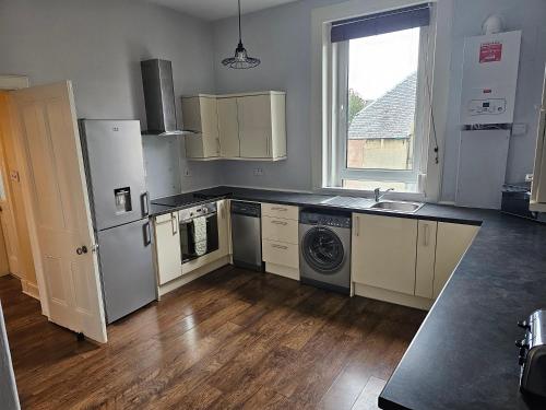 a kitchen with a refrigerator and a sink and a dishwasher at Snug - Abhainn Apartment in Helensburgh