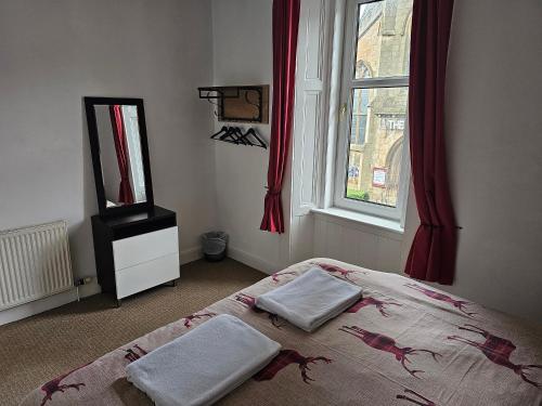 a bedroom with a bed with two towels on it at Snug - Abhainn Apartment in Helensburgh