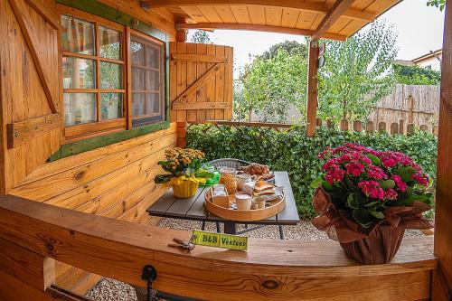 un patio de madera con una mesa con comida y flores en B&b Ventuno IUN0058 en Barùmini