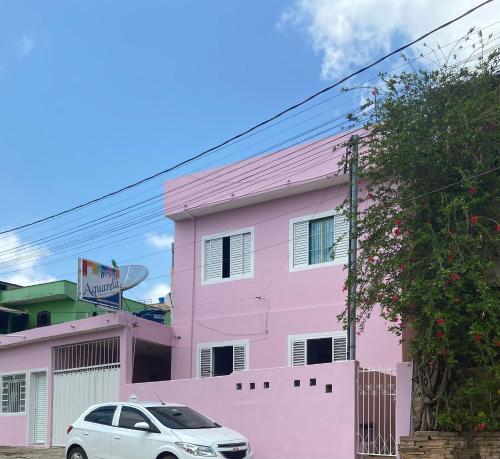 a pink house with a car parked in front of it at Pousada Aquarela in São Thomé das Letras