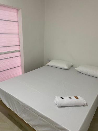 ein weißes Bett mit einem Handtuch darüber in der Unterkunft MOTEL SANTORINI in Baranoa
