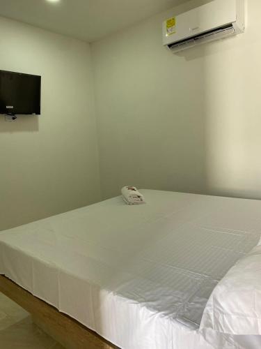 ein weißes Bett in einem Zimmer mit einem TV in der Unterkunft MOTEL SANTORINI in Baranoa