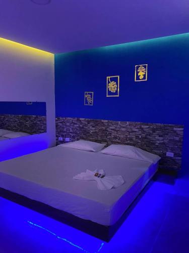 Schlafzimmer mit einem Bett mit blauem Licht in der Unterkunft MOTEL SANTORINI in Baranoa