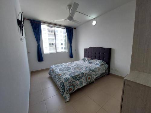a bedroom with a bed and a window with blue curtains at Aqualina Orange Hermoso Apartamento Piso 3 Vista a Piscina in Girardot