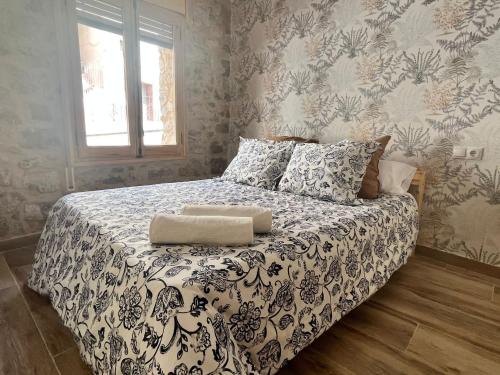 a bedroom with a bed with a black and white comforter at El Brollador in Corbera