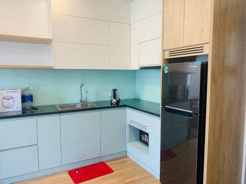 a kitchen with white cabinets and a black refrigerator at V-Homestay in Hai Phong
