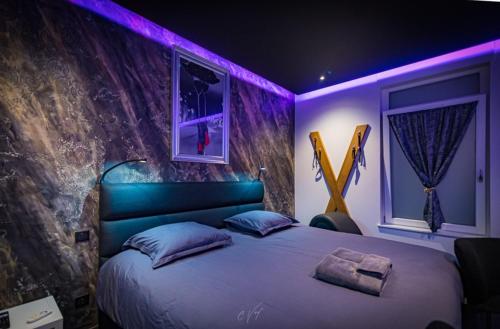 a bedroom with a large bed with purple lighting at spa de la quarterelle LOVE ROOM 88 VOSGES in Remiremont