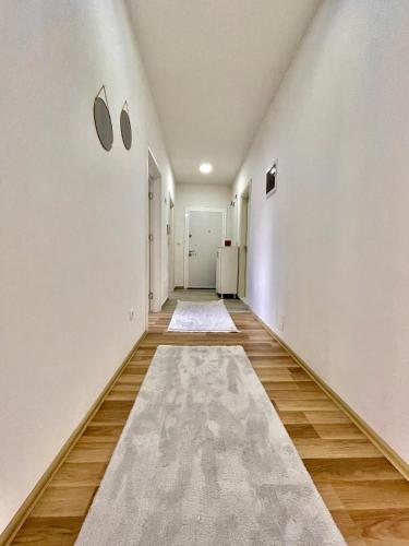 un couloir vide avec des murs blancs et un tapis au sol dans l'établissement Entire Apartment - near the Center, à Pristina