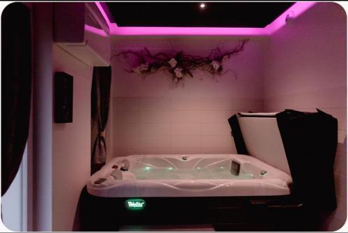 a bath tub in a bathroom with purple lighting at spa de la quarterelle LOVE ROOM 88 VOSGES in Remiremont