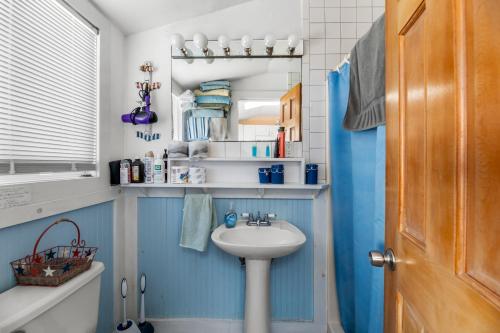 baño con lavabo blanco y paredes azules en The Blue Parrot Cottage, en Ocean Beach