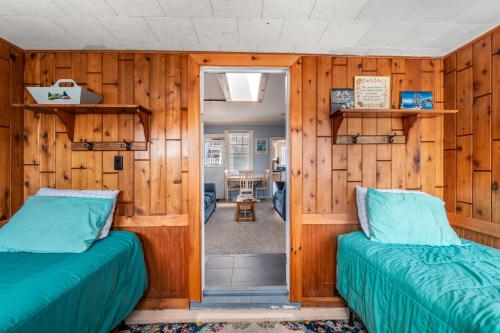 two beds in a room with wooden walls at The Blue Parrot Cottage in Ocean Beach