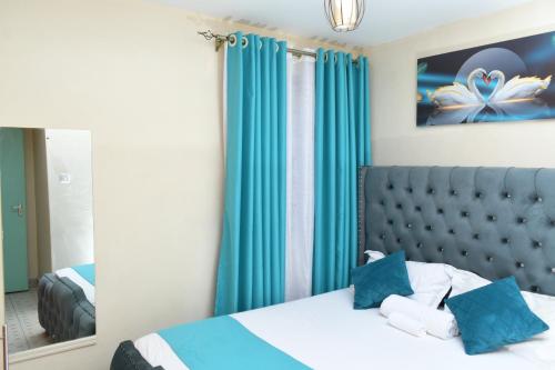 1 dormitorio con 1 cama con cortinas azules y espejo en Nomads Luxurious Homes, en Nairobi