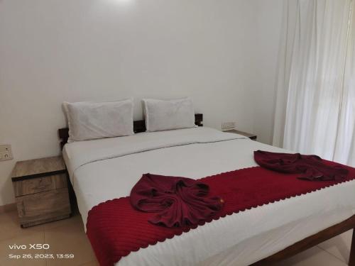 a bed with a red and white blanket on it at Ronne's ZED Penthouse and apartment in Arpora