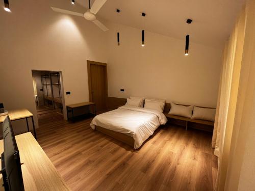 a bedroom with a white bed and wooden floors at The Holiday Home in Srinagar