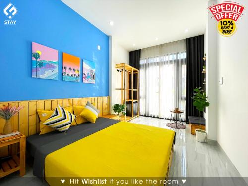 a bedroom with a yellow bed and a blue wall at FSTAY - COZY AND PEACEFUL HOMESTAY DA NANG in Da Nang