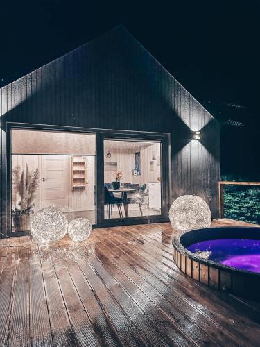 a patio with a hot tub and chairs on a wooden floor at Ežerėja 