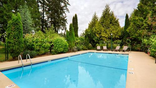 una piscina en un patio con sillas y árboles en Best Western Cowichan Valley Inn, en Duncan