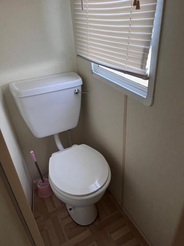 Un baño con inodoro blanco y ventana. en S422 Golden Palm 8 Berth Caravan, en Chapel St. Leonards