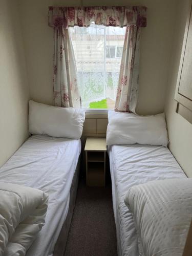 Habitación pequeña con 2 camas individuales y ventana en S422 Golden Palm 8 Berth Caravan, en Chapel St. Leonards