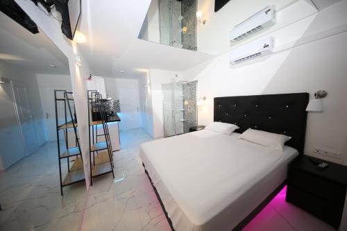 Un dormitorio con una cama blanca y una escalera en Studio Indecent, en Cap d'Agde