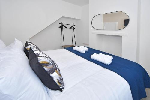 uma cama branca com duas almofadas e um espelho em Unity House - A Stylish Haven with 3 Bedrooms, Perfect for Your Tranquil Getaway em Crewe