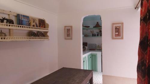 a kitchen with white walls and a table and shelves at Logement entier riad Dar Sana in Marrakesh