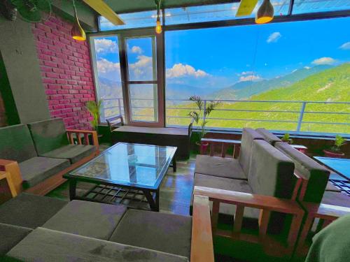 sala de estar con sofá y mesa de cristal en Pinerock Resort, Mussoorie ! Luxury Rooms ! Mountain View ! Open Terrace ! Cafe, en Mussoorie
