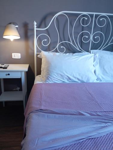 a bed with a metal headboard and a table with a lamp at Peppinella Affittacamere in Cetraro