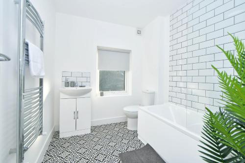 uma casa de banho com uma banheira, um WC e um lavatório. em Unity House - A Stylish Haven with 3 Bedrooms, Perfect for Your Tranquil Getaway em Crewe