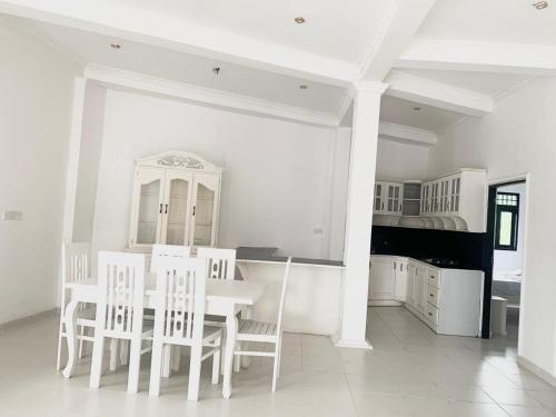 a white kitchen with a white table and chairs at Changami Residence in Nugegoda