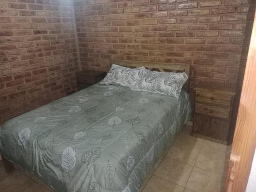 a bedroom with a bed with a brick wall at Complejo Hatun Yaya in Mendoza