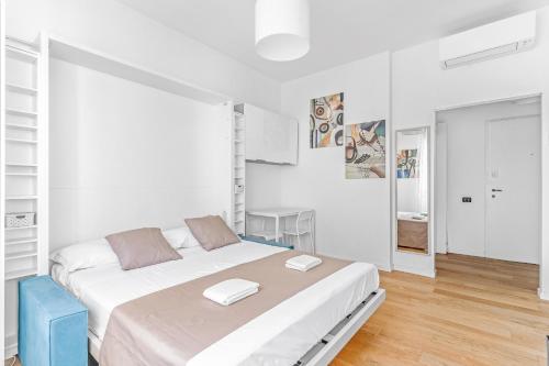 una camera bianca con un grande letto e un tavolo di Casa da Suite Compatta a Milano