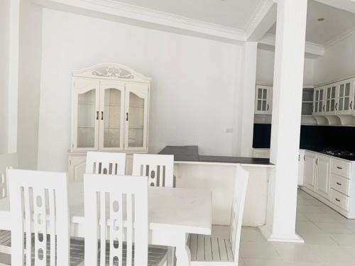 a white kitchen with white cabinets and white chairs at Changami Residence in Nugegoda
