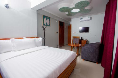 a bedroom with a large white bed and a chair at HADJENS HOTEL in Mwanza